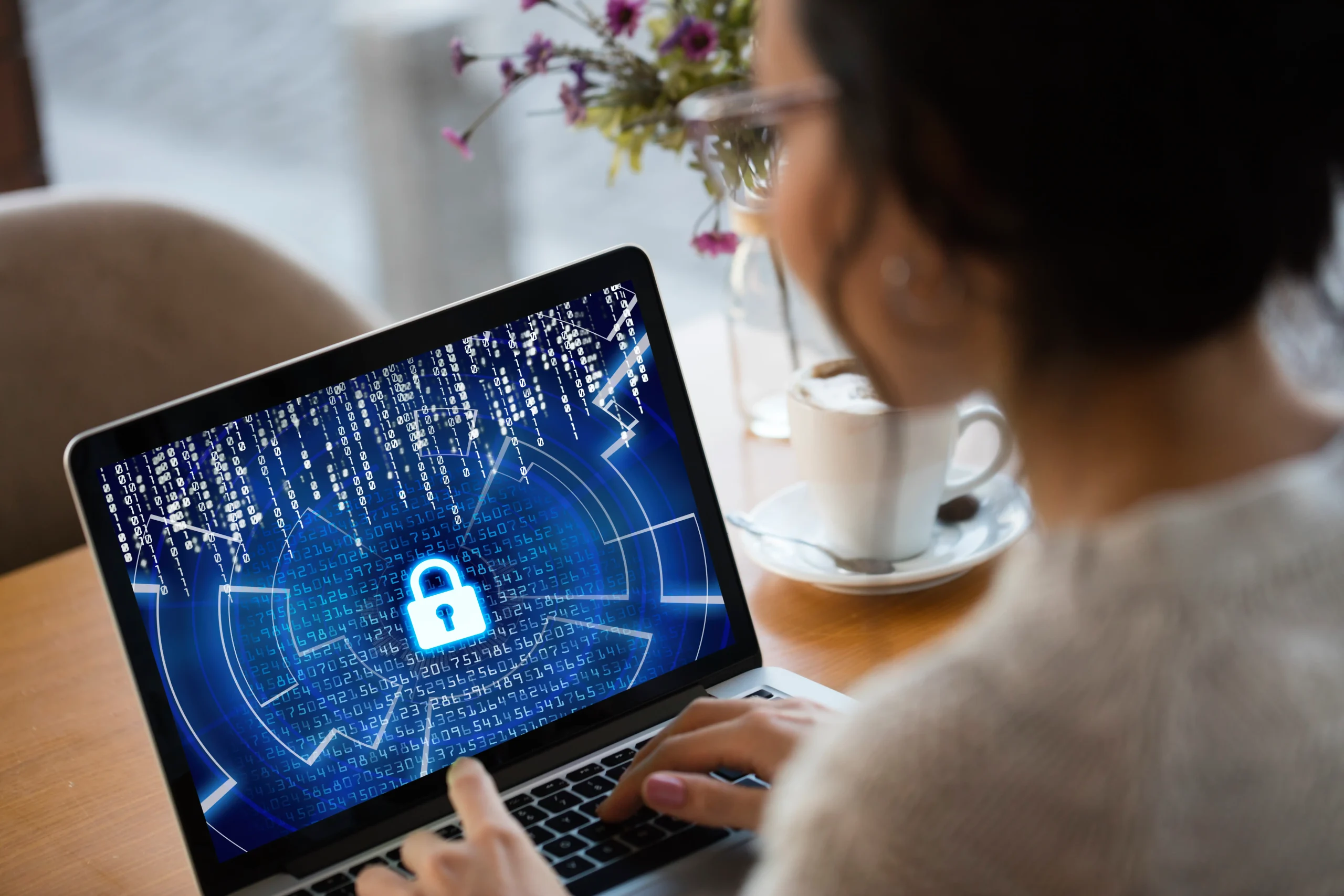 A person working on a laptop displaying a digital security interface with a lock icon amid coding data streams, symbolizing cybersecurity measures for IT Solutions.