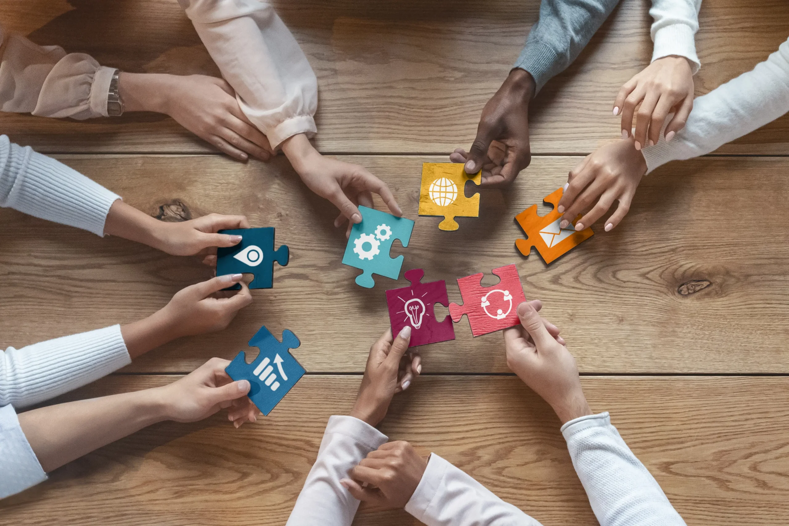 Diverse team assembling jigsaw puzzle pieces symbolizing collaboration, resource integration, and IT Solutions solution building.